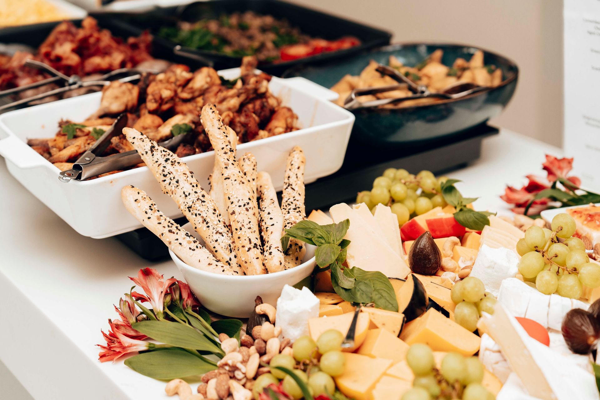 A mouth-watering assortment of cheeses, breadsticks, and fruits in a buffet setting. Perfect for catering events.