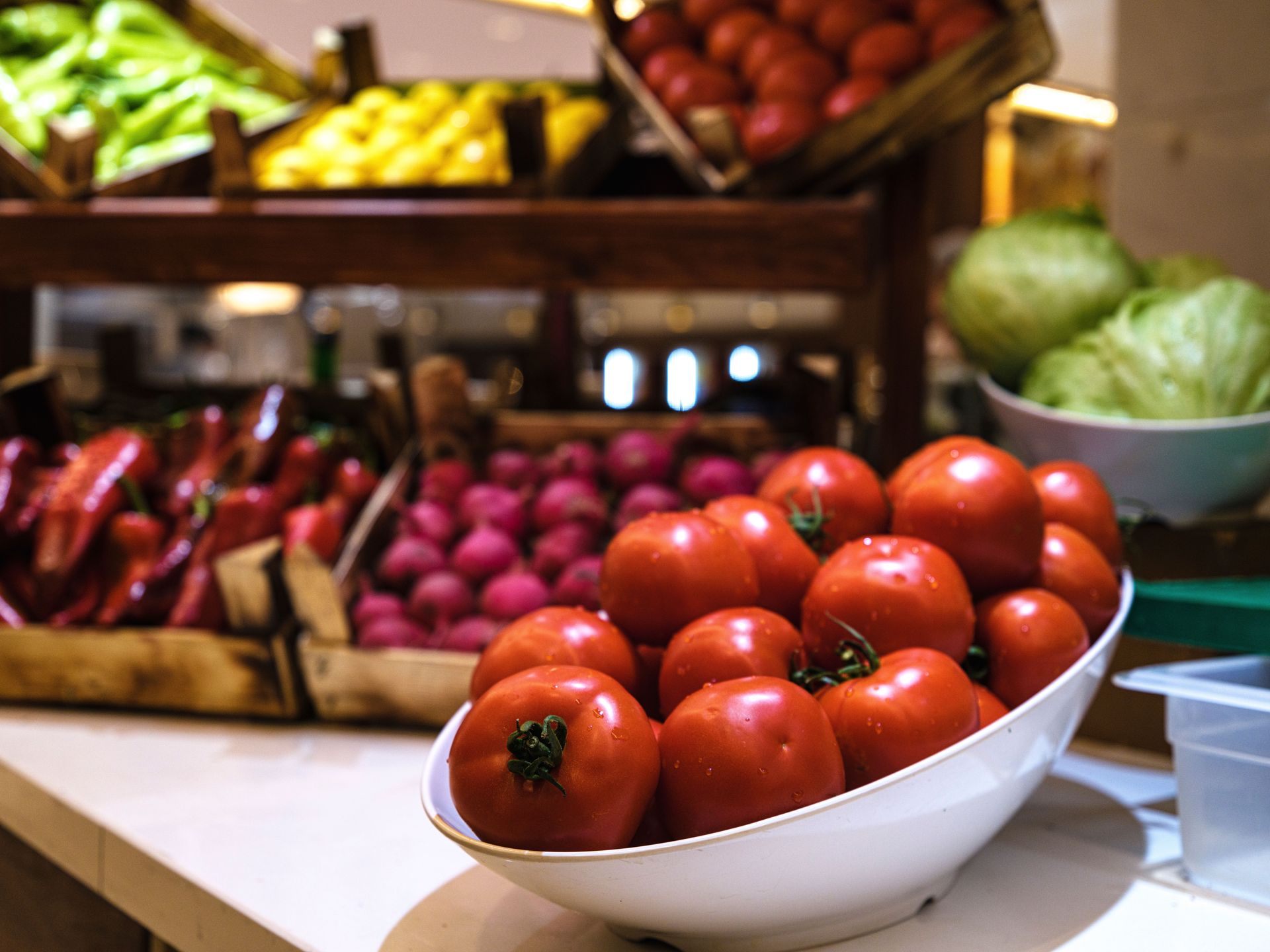 Close-up view of fresh tomatoes arranged with other vegetables in a market setting, highlighting organic produce.