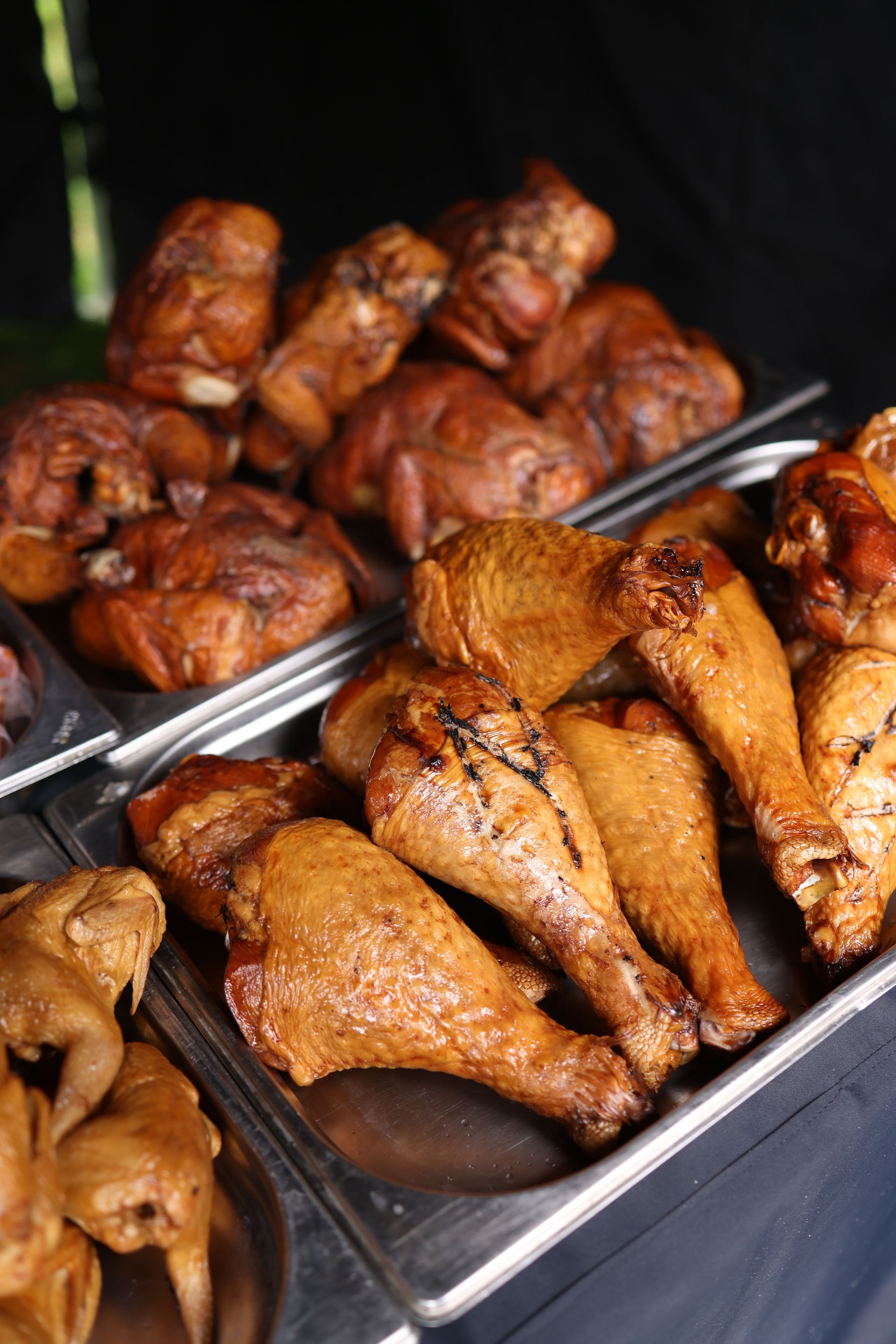 A variety of grilled meats including chicken drumsticks and smoked meats on display.
